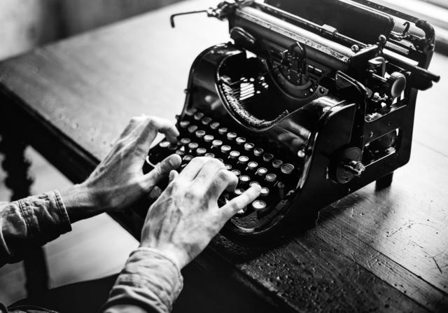 Monochrome view of hands typing on an old typewriter